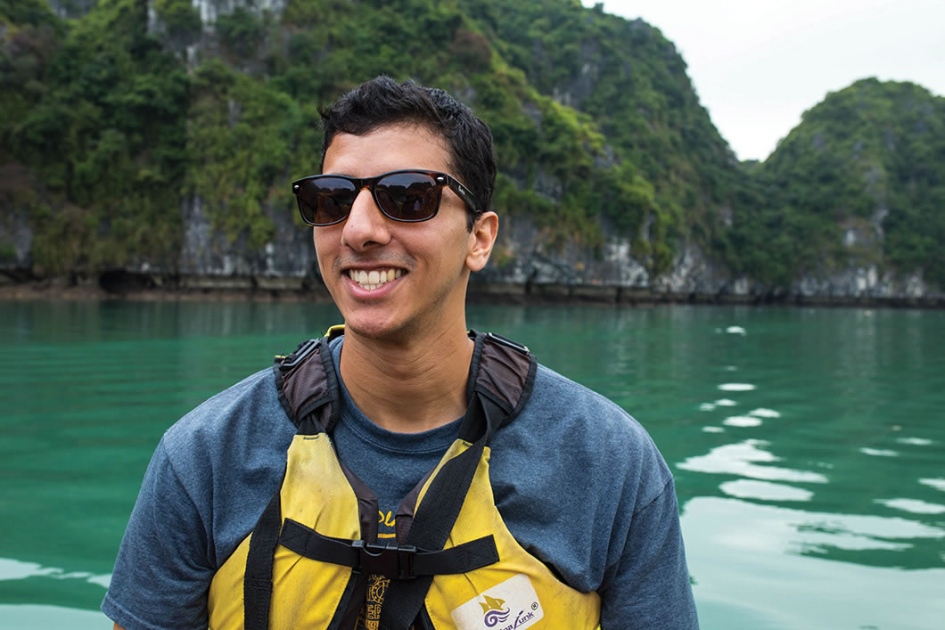 Nitin Savant wearing life jacket on boat with sea and cliffs behind him.