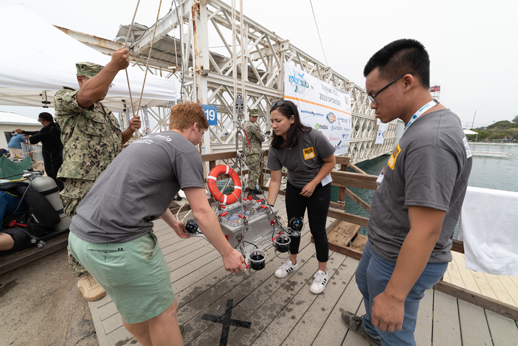 Students move robot sub with crane.