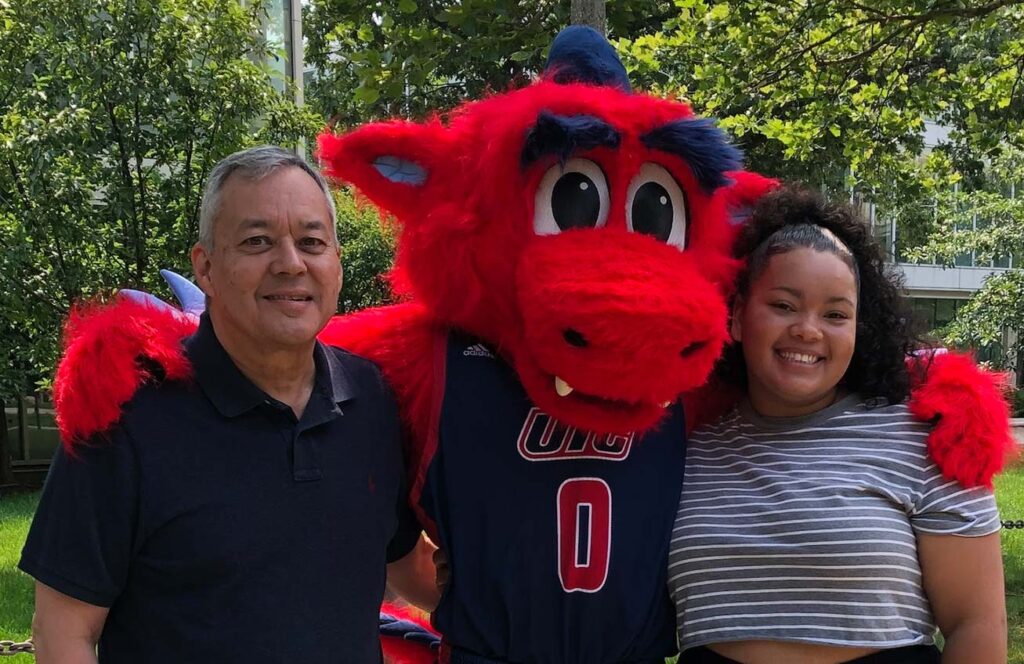 Bernie Santarsiero posing with student on either side of university  mascot