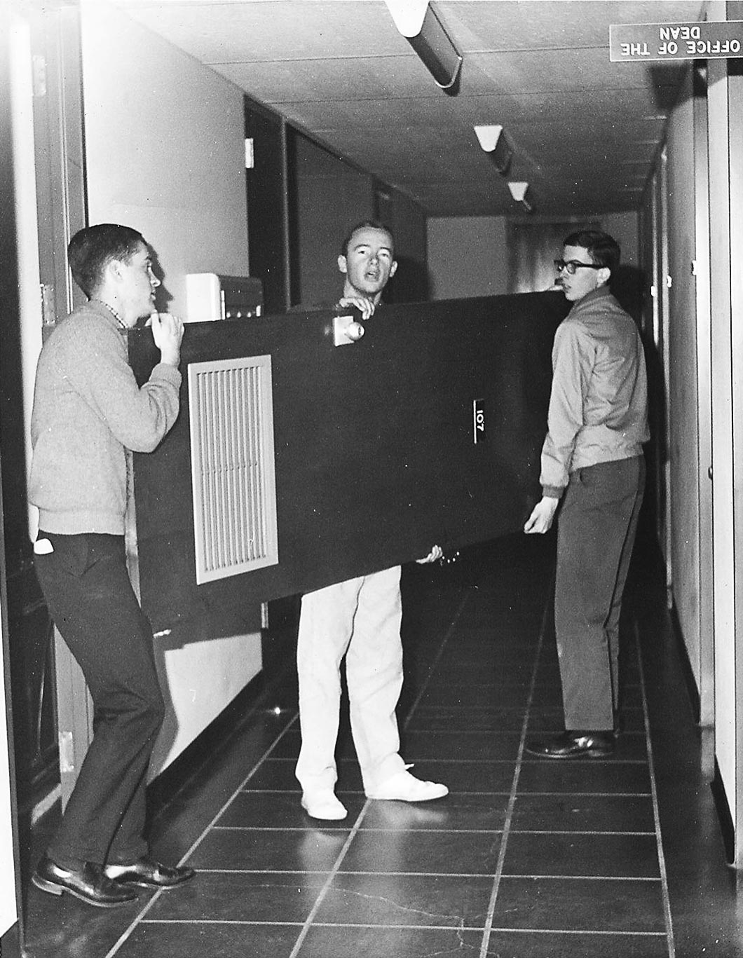 3 students carry removed office door.