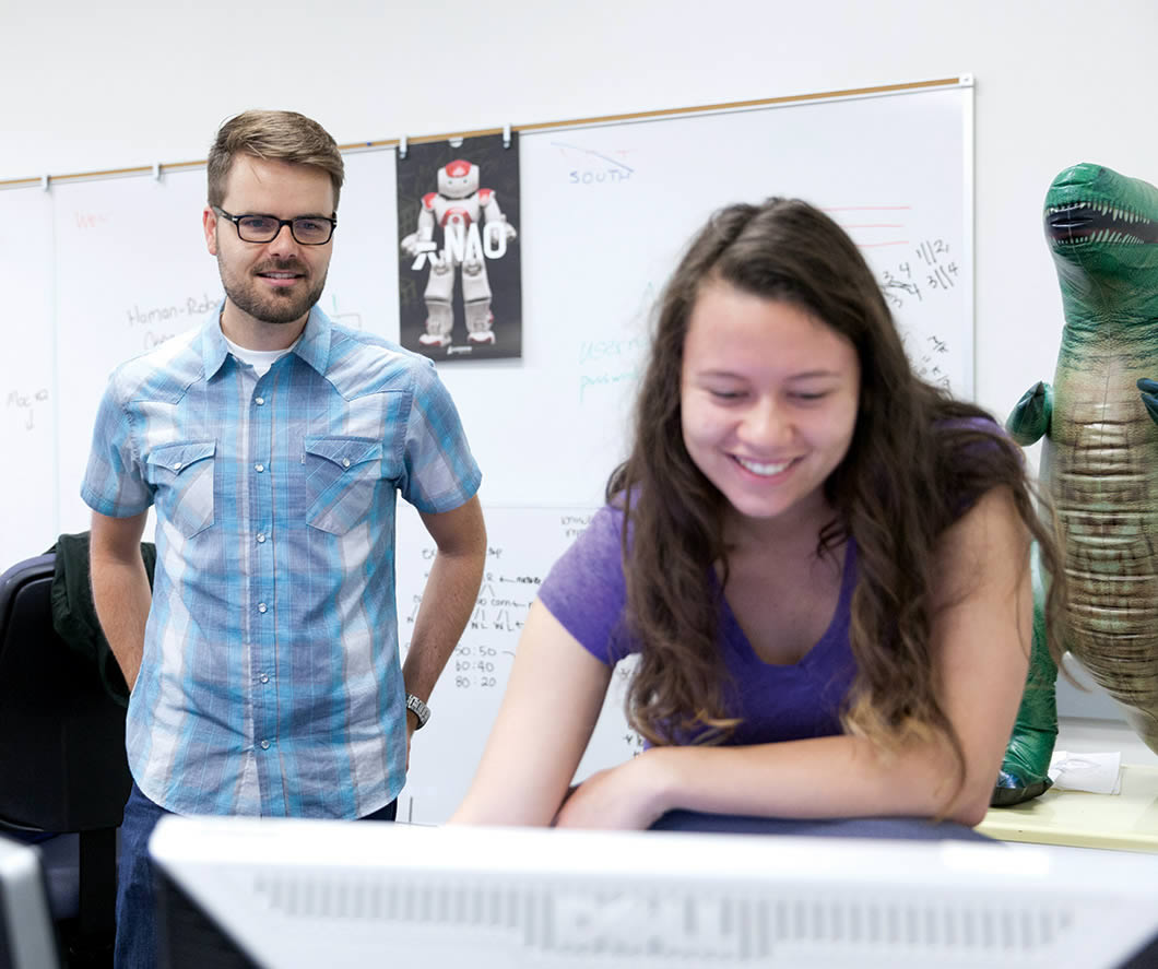 Jim Boerkoel looks over the shoulder of a student looking at a computer monitor.