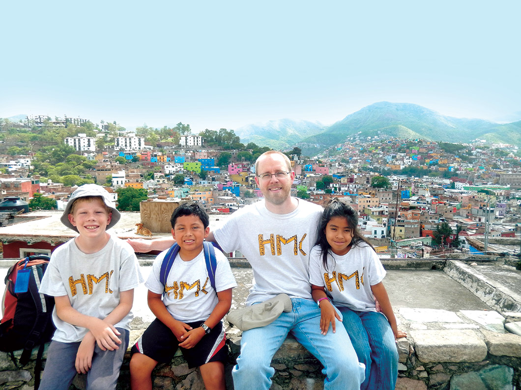 David Vosburg and children sitting on wall overlooking city.