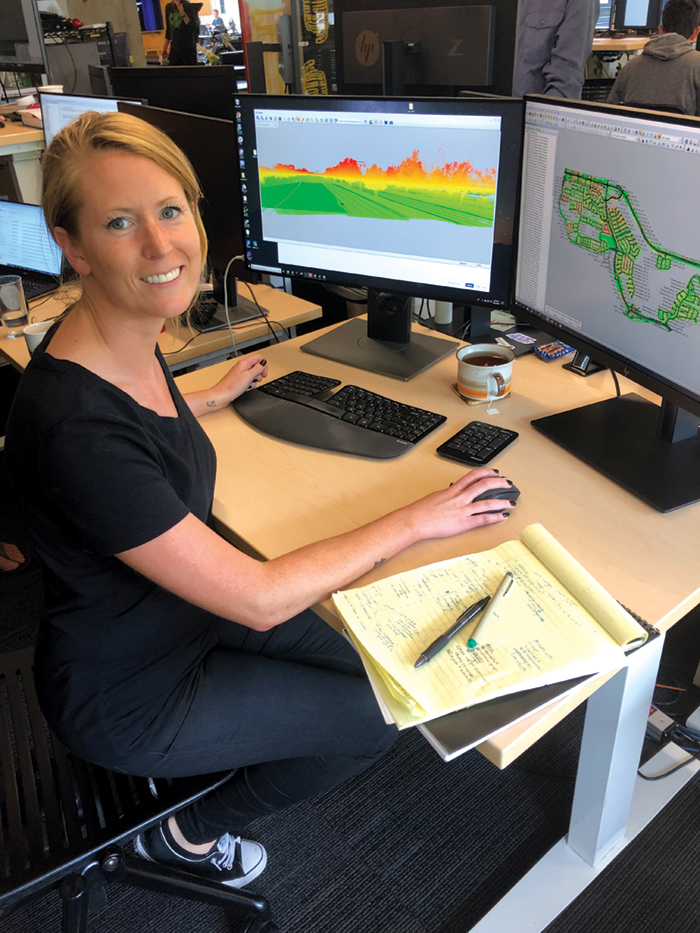 Audrey Lawrence at desk in front of two monitors.