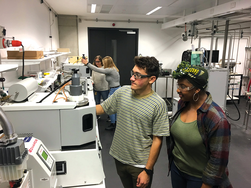 Four people in lab working with testing machines.