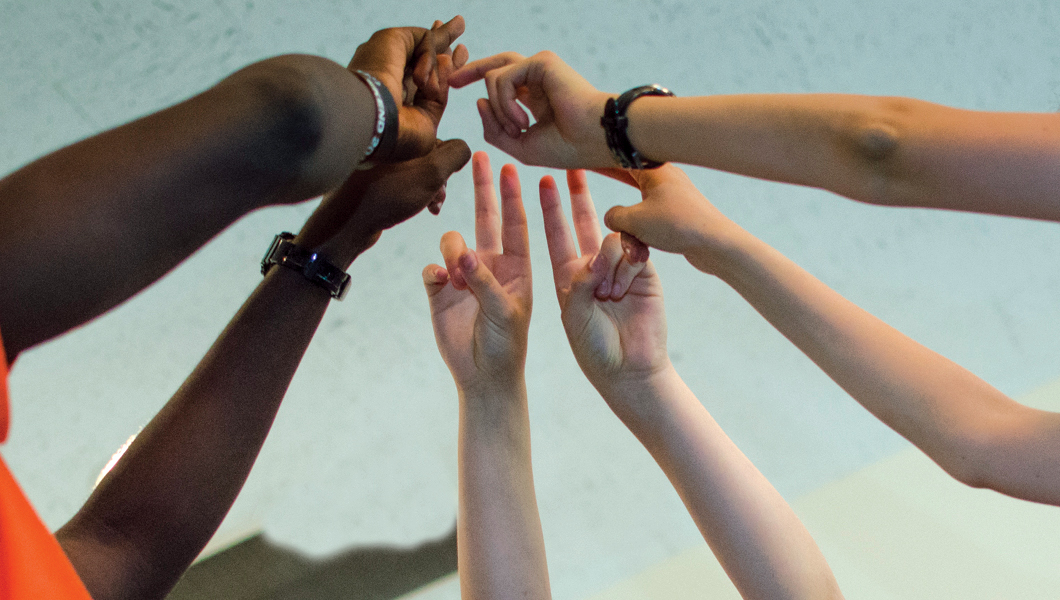 Five hands reaching up to the sky