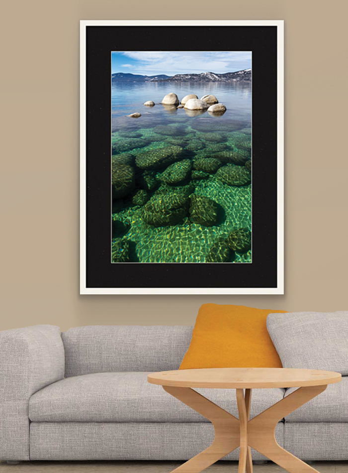 Lake photo in frame on wall over couch.