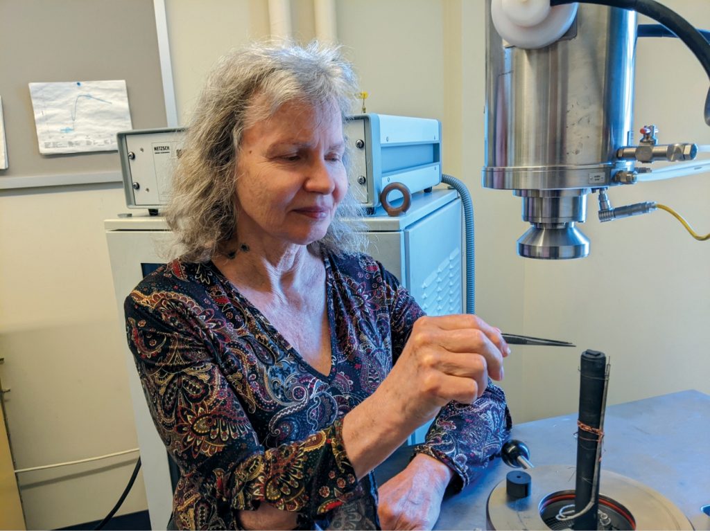 Anne Hofmeister places sample in scientific equipment.