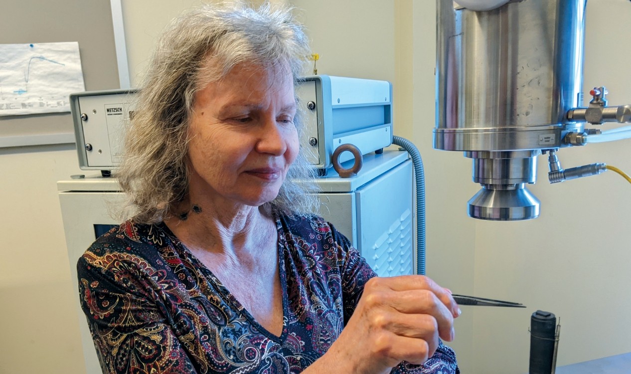 Anne Hofmeister places sample in scientific equipment.