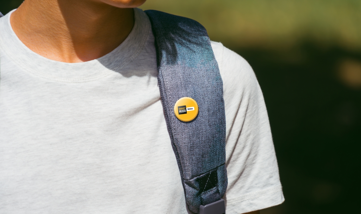 Image of a Harvey Mudd Votes button on the strap of a student backpack